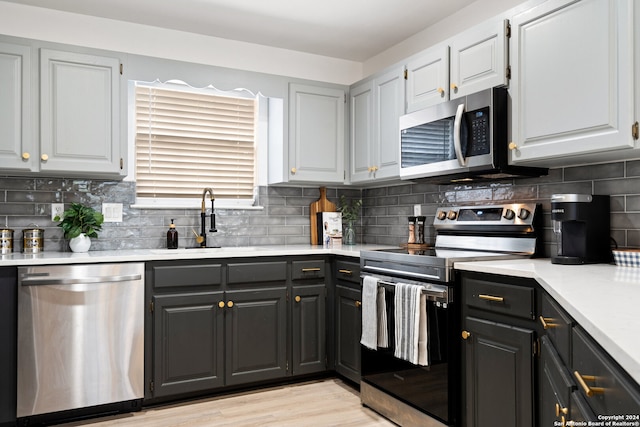 kitchen with appliances with stainless steel finishes, light hardwood / wood-style floors, sink, and tasteful backsplash