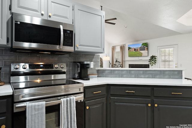 kitchen with gray cabinets, ceiling fan, stainless steel appliances, and tasteful backsplash