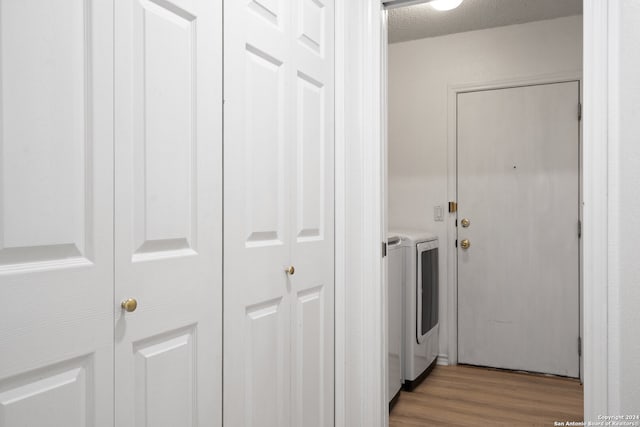 laundry area with light wood-type flooring, washer and clothes dryer, and a textured ceiling