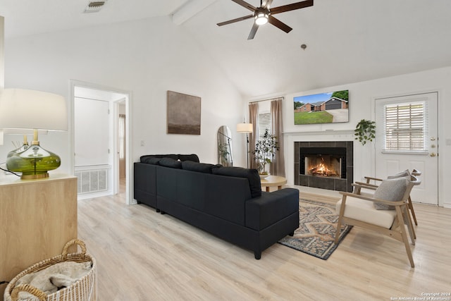 living room with light hardwood / wood-style floors, beamed ceiling, a tiled fireplace, high vaulted ceiling, and ceiling fan