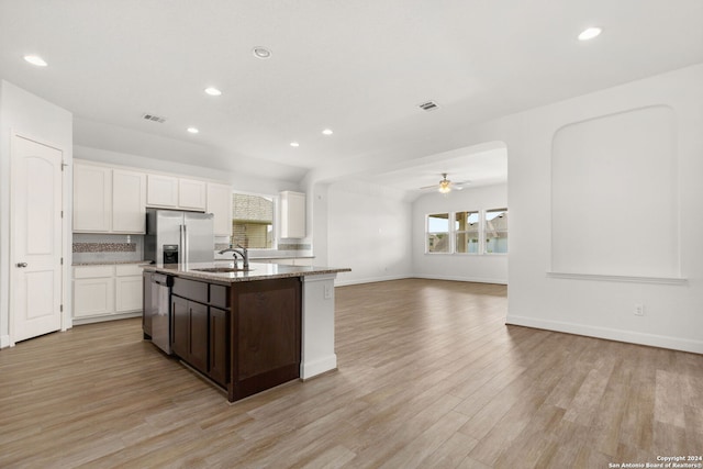 kitchen with light hardwood / wood-style floors, an island with sink, white cabinets, stainless steel appliances, and ceiling fan