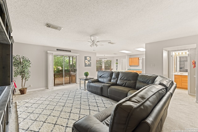 carpeted living room featuring ceiling fan and a textured ceiling