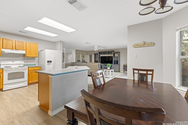 kitchen with a textured ceiling, ceiling fan with notable chandelier, white appliances, and light hardwood / wood-style flooring