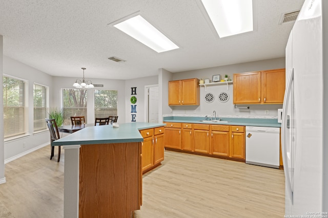 kitchen with white appliances, decorative light fixtures, light hardwood / wood-style floors, and a kitchen island