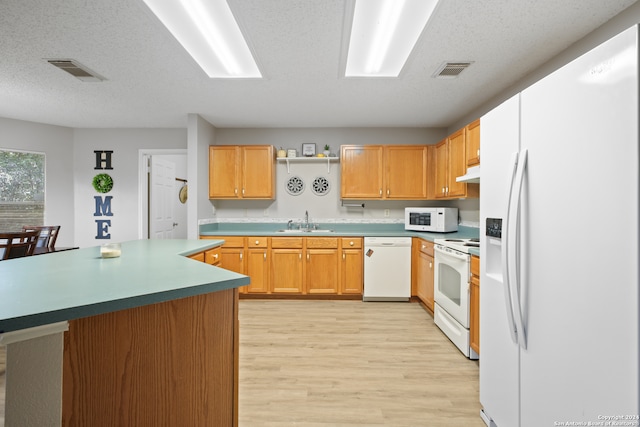 kitchen with a textured ceiling, light hardwood / wood-style floors, sink, a kitchen island, and white appliances