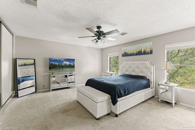 carpeted bedroom featuring multiple windows, ceiling fan, and a textured ceiling