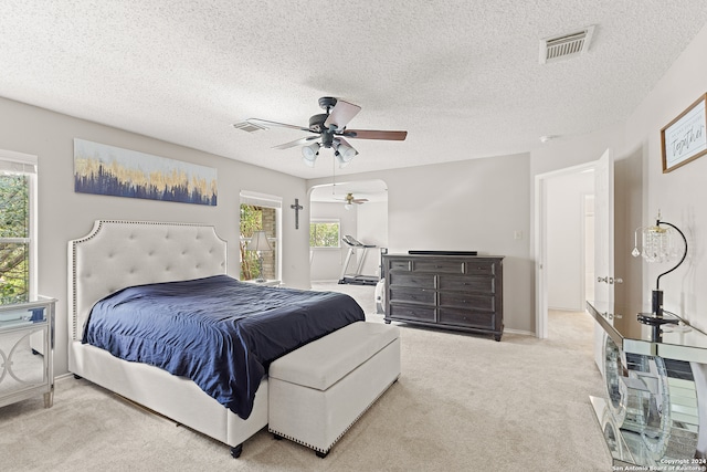 bedroom with light carpet, ceiling fan, and a textured ceiling