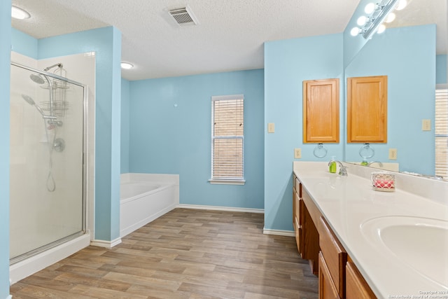 bathroom with vanity, a textured ceiling, independent shower and bath, and hardwood / wood-style floors