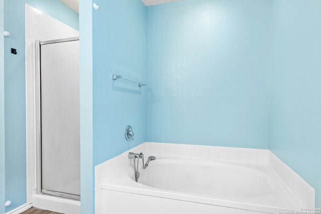 bathroom with shower with separate bathtub and a textured ceiling