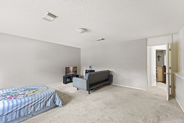 bedroom featuring a textured ceiling and light colored carpet