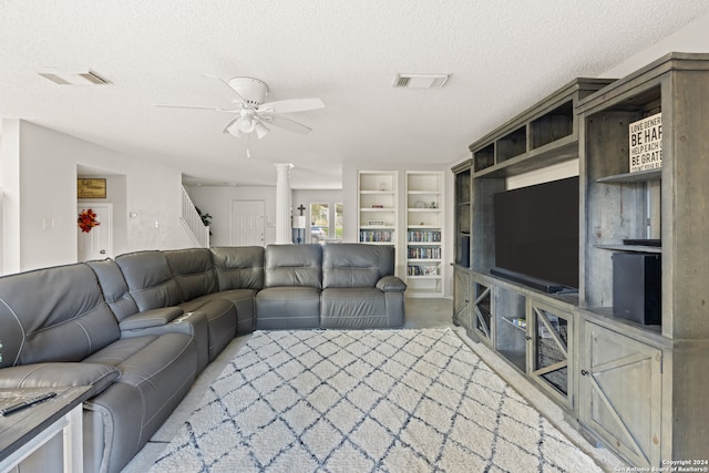 living room with decorative columns, ceiling fan, and a textured ceiling