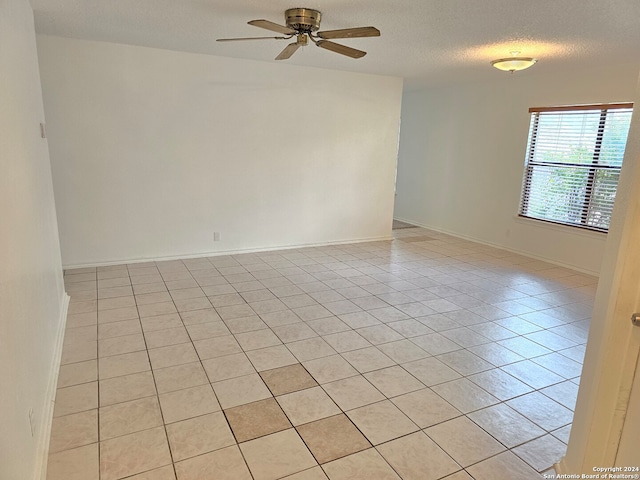 tiled spare room featuring a textured ceiling and ceiling fan