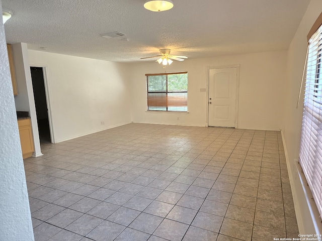 tiled empty room with a textured ceiling and ceiling fan