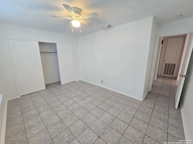 unfurnished bedroom with a closet, ceiling fan, light tile patterned flooring, and a textured ceiling