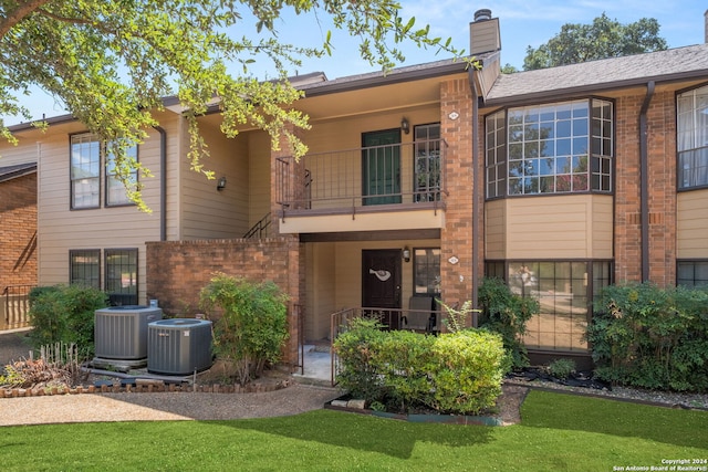 back of house with a balcony, cooling unit, and a yard