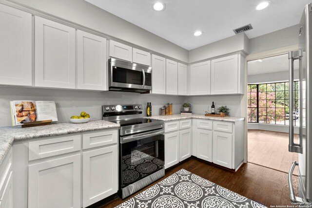 kitchen featuring stainless steel appliances, white cabinets, light stone counters, and dark hardwood / wood-style flooring