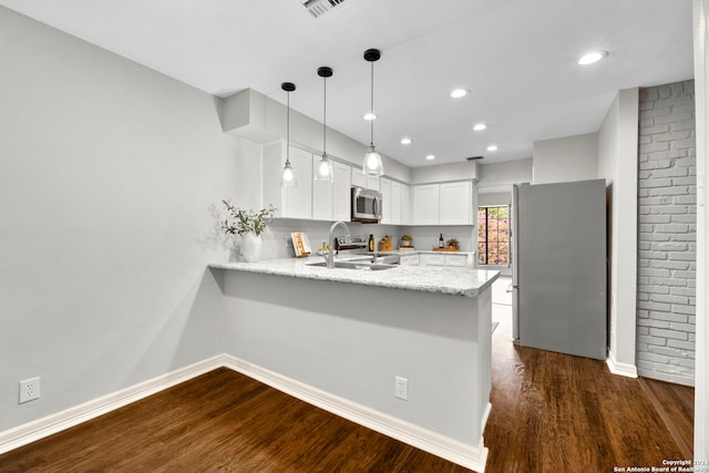 kitchen with white cabinets, hanging light fixtures, kitchen peninsula, stainless steel appliances, and dark hardwood / wood-style flooring