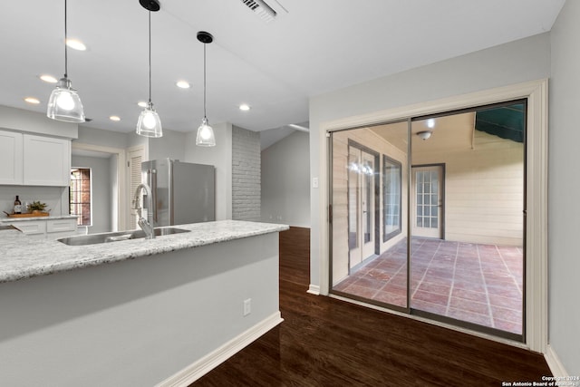 kitchen featuring dark wood-type flooring, sink, white cabinets, decorative light fixtures, and stainless steel fridge