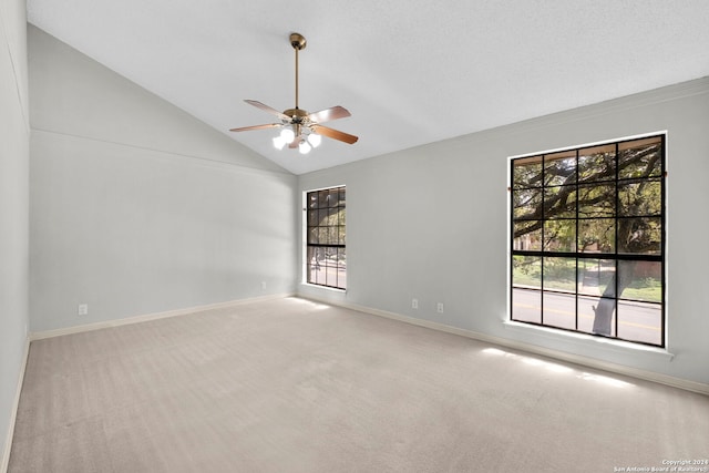 carpeted empty room with ceiling fan, plenty of natural light, and vaulted ceiling