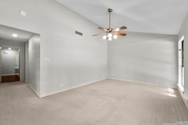 empty room featuring vaulted ceiling, ceiling fan, and light colored carpet