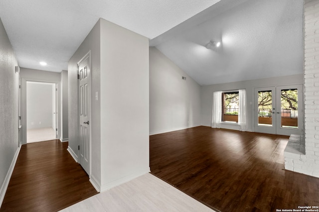 unfurnished room featuring a textured ceiling, vaulted ceiling, and dark hardwood / wood-style flooring