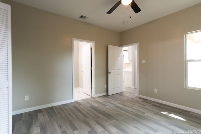 unfurnished bedroom with connected bathroom, ceiling fan, and hardwood / wood-style flooring