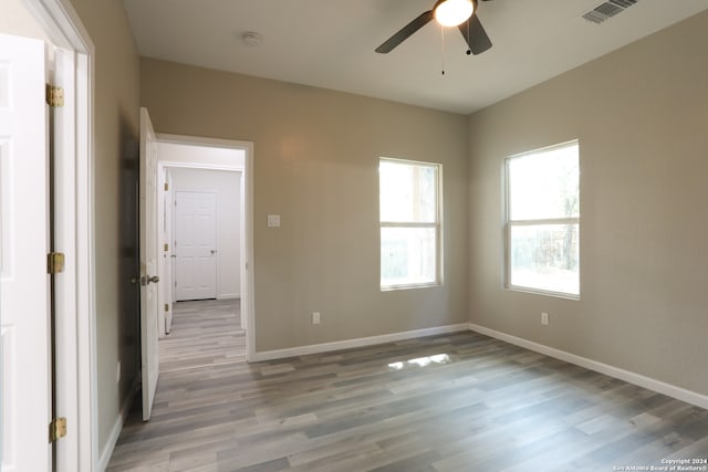 empty room with ceiling fan and light hardwood / wood-style flooring