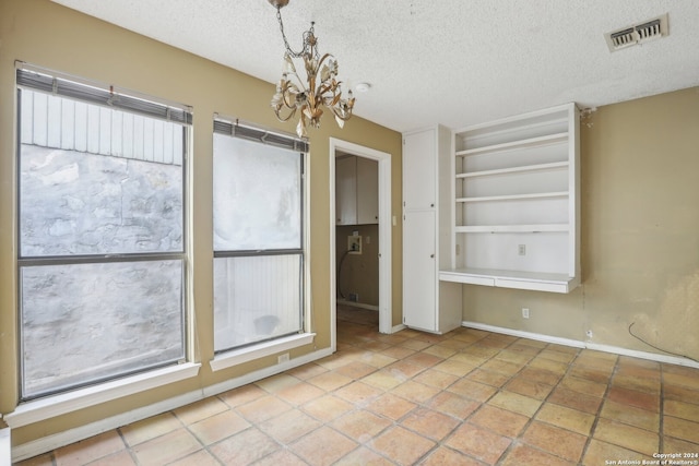 unfurnished room with a notable chandelier and a textured ceiling