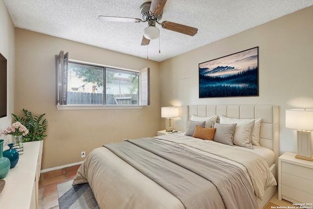 tiled bedroom with ceiling fan and a textured ceiling