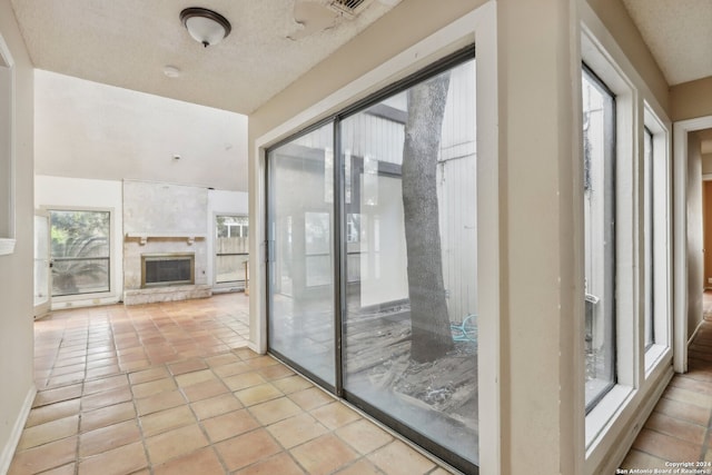 hallway with a textured ceiling, light tile patterned floors, and a healthy amount of sunlight