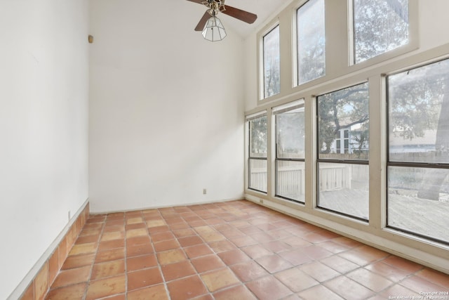 unfurnished room with ceiling fan, light tile patterned flooring, and a high ceiling