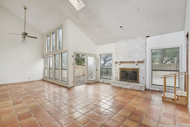 unfurnished living room featuring a wealth of natural light, a large fireplace, ceiling fan, and high vaulted ceiling