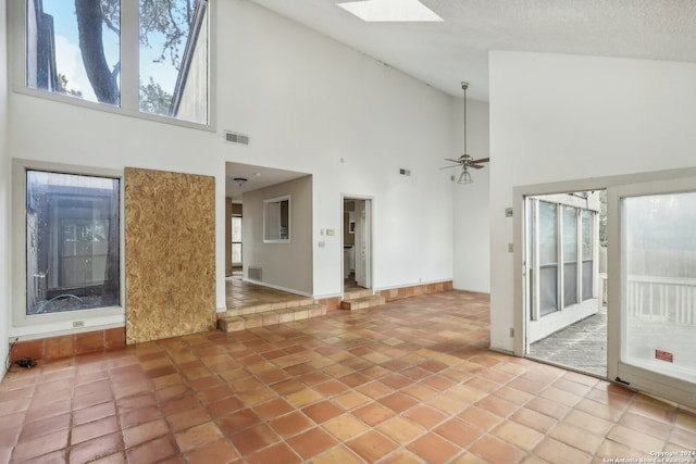 unfurnished living room featuring ceiling fan, a textured ceiling, high vaulted ceiling, and tile patterned floors