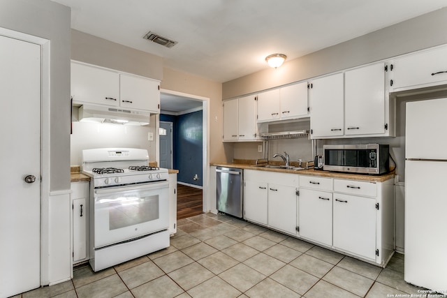 kitchen featuring sink, white cabinetry, stainless steel appliances, and light tile patterned floors