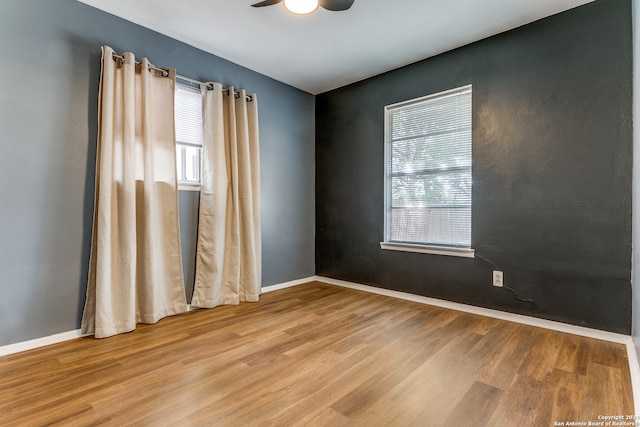 spare room with light wood-type flooring, a healthy amount of sunlight, and ceiling fan