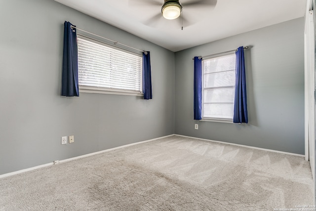 carpeted empty room with ceiling fan and a wealth of natural light