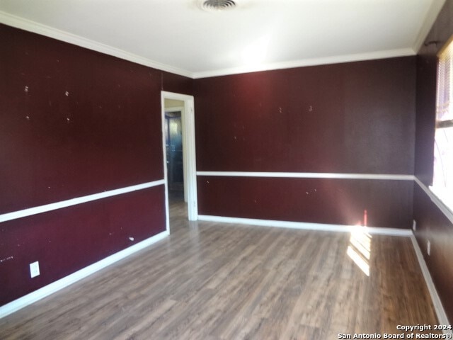 empty room featuring wood-type flooring and ornamental molding