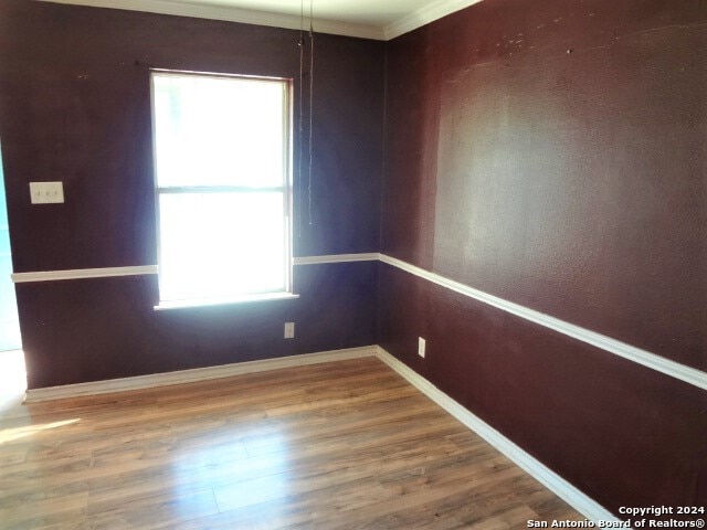 unfurnished room with hardwood / wood-style flooring and crown molding