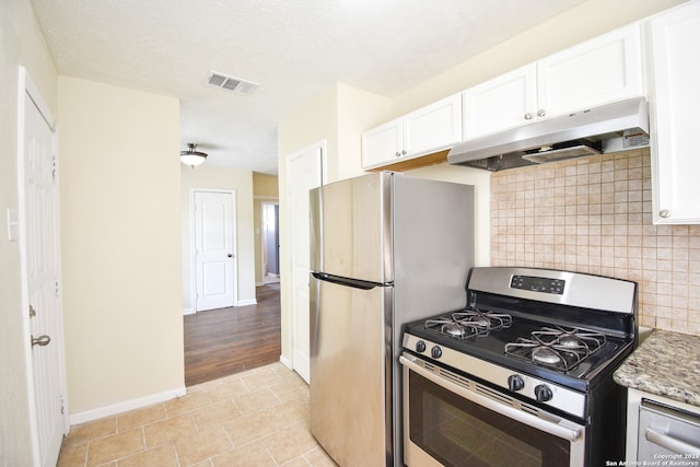 kitchen featuring tasteful backsplash, light tile patterned flooring, stainless steel appliances, white cabinets, and light stone counters