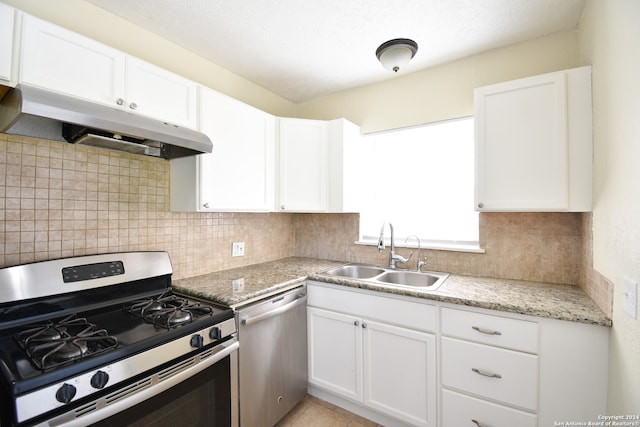 kitchen with sink, white cabinets, appliances with stainless steel finishes, light stone counters, and tasteful backsplash