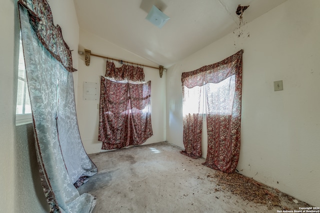 empty room with lofted ceiling, concrete floors, and a healthy amount of sunlight