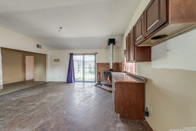 kitchen featuring lofted ceiling, a wood stove, and concrete floors