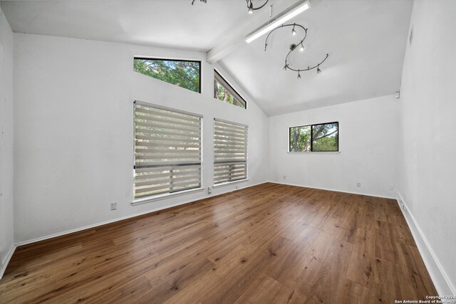 spare room with wood-type flooring, lofted ceiling with beams, and plenty of natural light