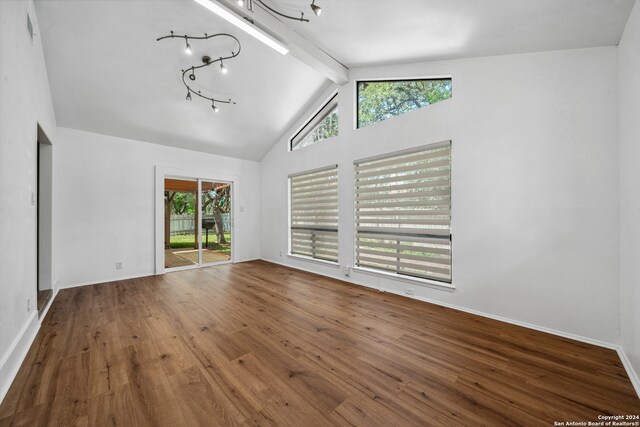 spare room featuring beam ceiling, hardwood / wood-style floors, high vaulted ceiling, and a wealth of natural light