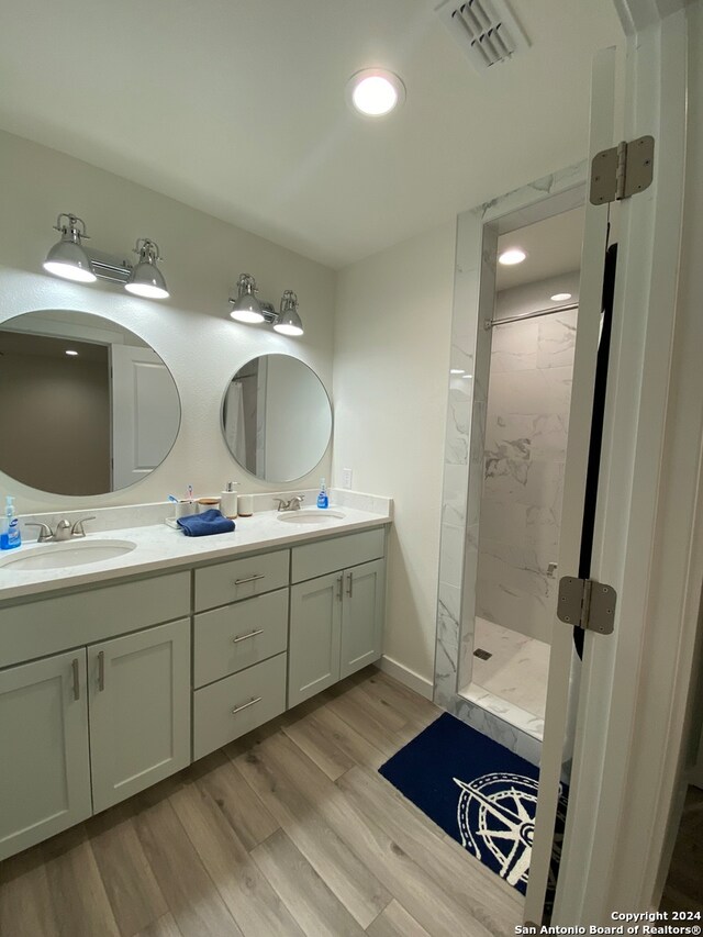 bathroom featuring hardwood / wood-style floors, vanity, and tiled shower