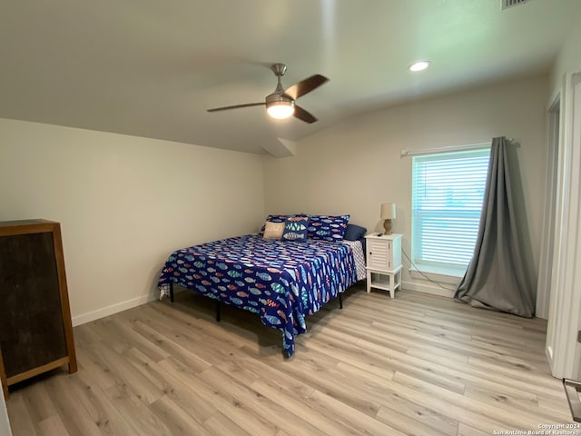 bedroom featuring light hardwood / wood-style floors, vaulted ceiling, and ceiling fan