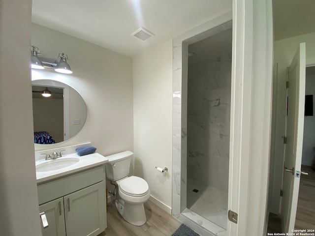 bathroom featuring vanity, a tile shower, toilet, and hardwood / wood-style flooring