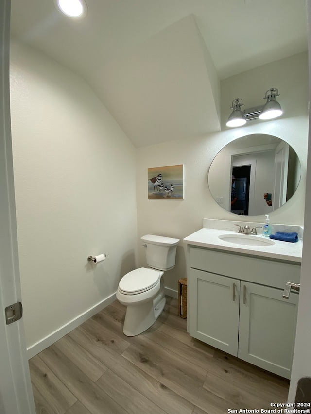 bathroom featuring hardwood / wood-style floors, vanity, toilet, and vaulted ceiling