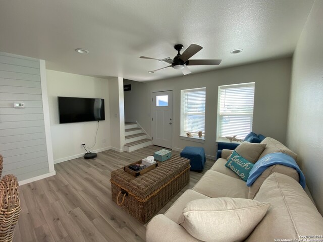 living room with light wood-type flooring, a textured ceiling, and ceiling fan