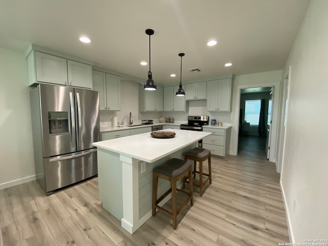 kitchen with light hardwood / wood-style flooring, stainless steel appliances, decorative light fixtures, and sink